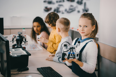 Shows four children in front of computers with robots they have build. To illustrate children doing robotics and learning how to code.