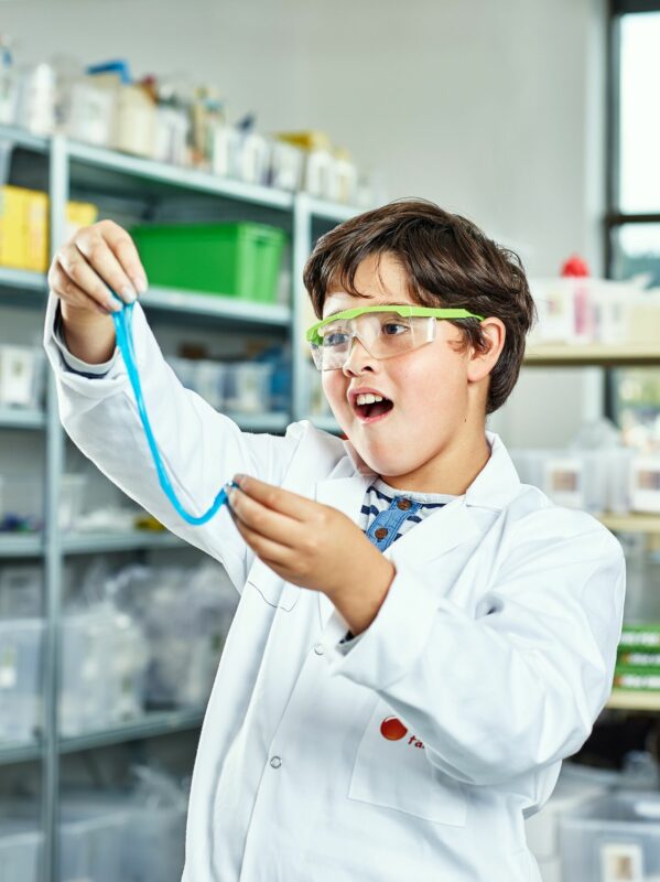 Shows a boy playing with slime made with glue and contact lens solution. Illustrates how this slime can be stretched quite long.